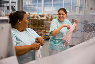 Zwei Personen bei der Arbeit in der Großwäscherei Waschwerk
