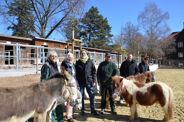 Mehrere Personen, die Esel und Ponys halten, stehen auf dem Reitplatz des Pferdehofs der Diakonie Stetten.