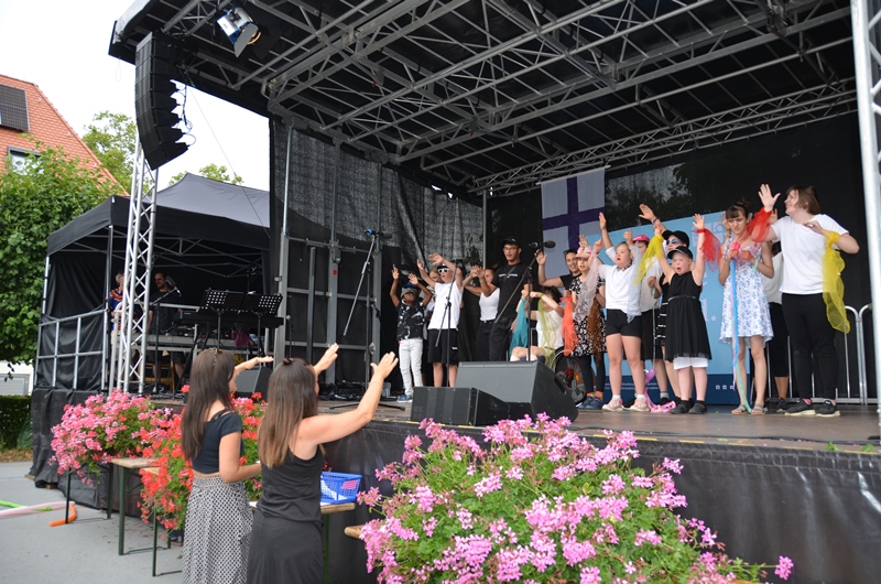 Schülerinnen und Schüler der Theodor-Dierlamm-Schule auf der Bühne, sie führen bei der Festfeier ihr Musikstück „Gemeinsam – Zusammen“ auf.