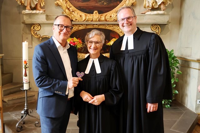 Vor dem Altar in der Schlosskapelle stehen (von links nach rechts) der Vorstandsvorsitzende der Diakonie Stetten, die Pfarrerin, die in den Ruhestand verabschiedet wurde und der stellvertretende Vorstandsvorsitzende der Diakonie Stetten. 