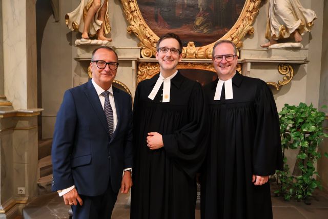 Die beiden Vorstände der Diakonie Stetten stehen rechts und links vom neuen leitenden Pfarrer vor dem Altar in der Schlosskapelle. Die beiden Vorstände der Diakonie Stetten stehen rechts und links vom neuen leitenden Pfarrer vor dem Altar in der Schlosskapelle.