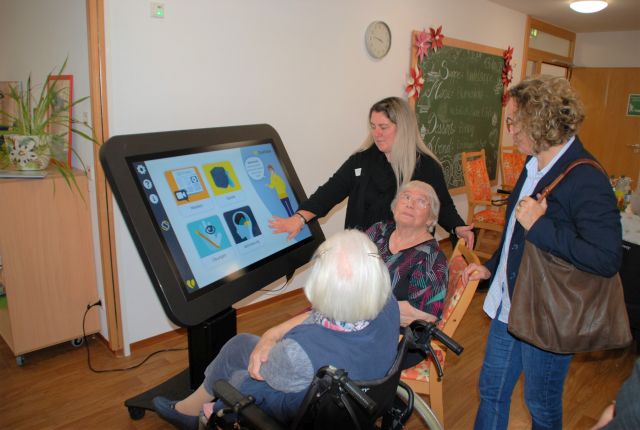 Zwei Personen sitzen und zwei weitere Personen stehen vor dem Care Table und beschäftigen sich damit. Zwei Personen sitzen und zwei weitere Personen stehen vor dem Care Table und beschäftigen sich damit.
