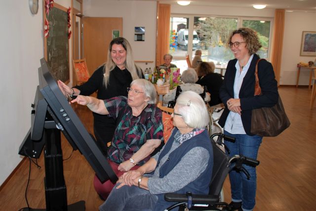 Zwei Personen sitzen und zwei weitere Personen stehen vor dem Care Table und beschäftigen sich damit, eine Person zeigt auf den Care Table. Zwei Personen sitzen und zwei weitere Personen stehen vor dem Care Table und beschäftigen sich damit, eine Person zeigt auf den Care Table.