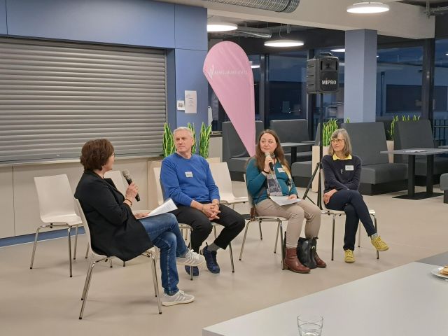 Vier Personen sitzen im Rahmen der Diskussionsrunde bei der Info-Veranstaltung der Arbeitsgruppe „Arbeit“ nebeneinander, zwei der Personen halten ein Mikrofon in den Händen