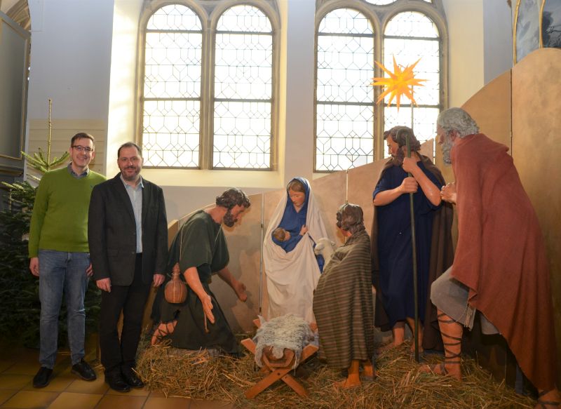 Zwei Personen stehen neben den lebensgroßen historischen Krippenfiguren in der Schlosskapelle.