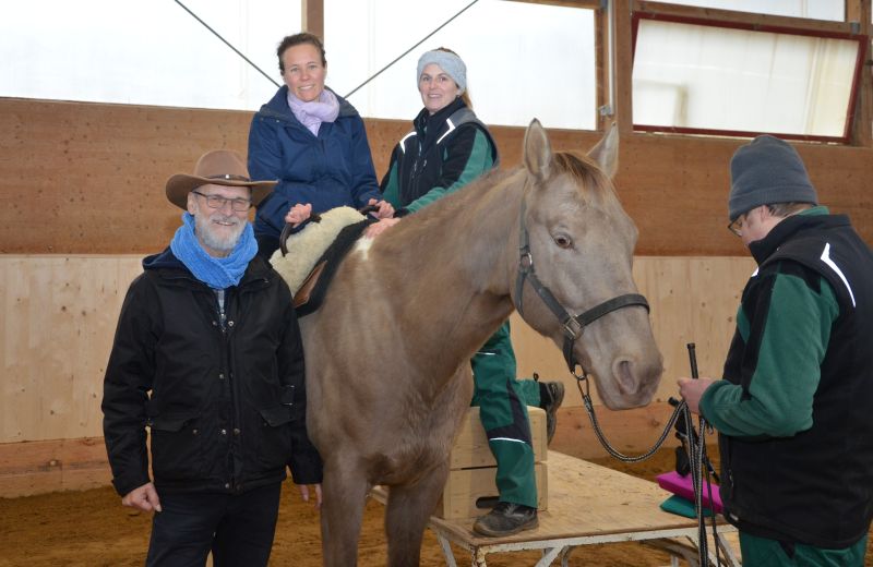 Therapiepferd Milo mit Reiterin zwischen einem Mitglied des Fördervereins und einer Therapeutin. 