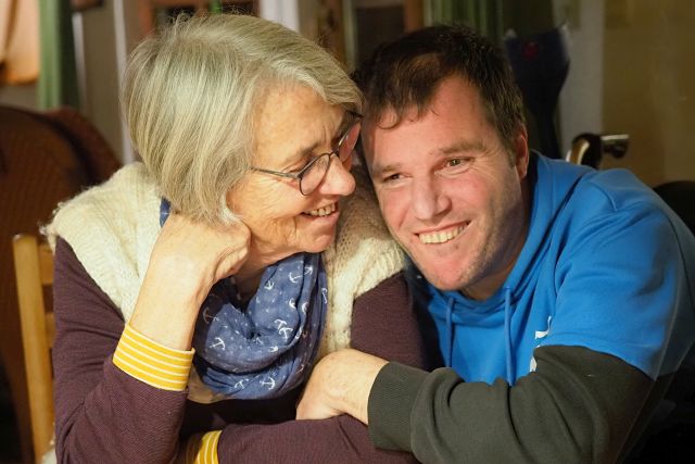 Zwei Personen sitzen eng nebeneinander und lächeln. (Foto: Gerhard Reider)