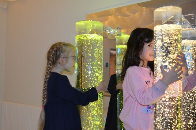 Zwei Kinder stehen an farbwechselnde Wassersäulen im neuen Snoezelenraum.