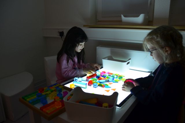 Zwei Kinder sitzen an einem Lichttisch im neuen Snoezelenraum.