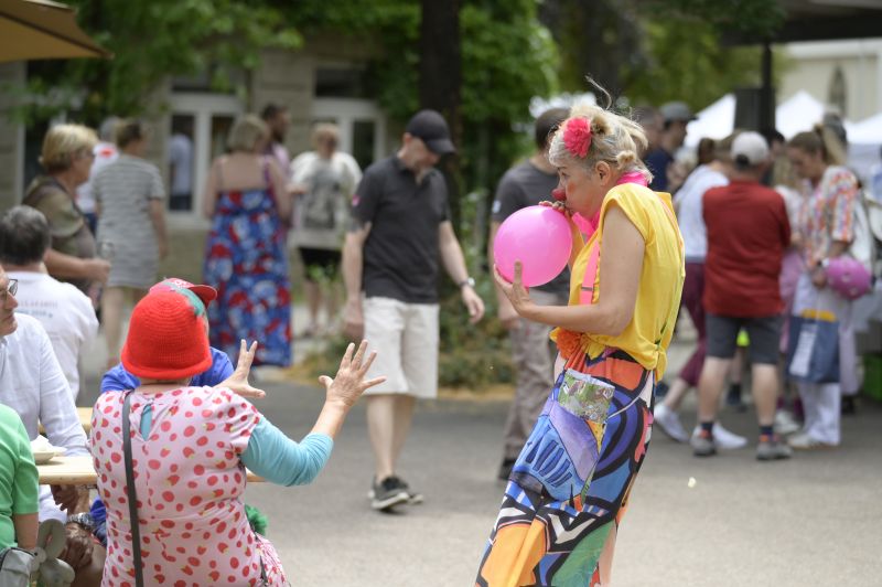 Eine Clownin bläst einen rosa Luftballon auf.