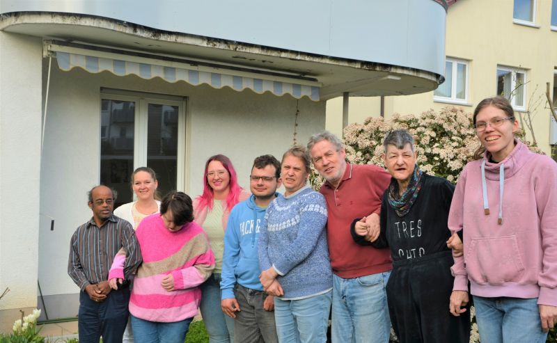 Die sieben Bewohnerinnen und Bewohner sowie 2 Mitarbeitende stehen nebeneinander im Garten. Die sieben Bewohnerinnen und Bewohner sowie 2 Mitarbeitende stehen nebeneinander im Garten.
